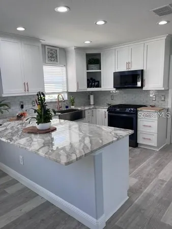 a kitchen with stainless steel appliances granite countertop a sink a stove top oven a counter space and cabinets