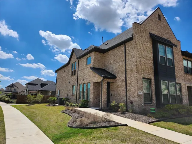 a view of a house with brick walls and a yard with plants