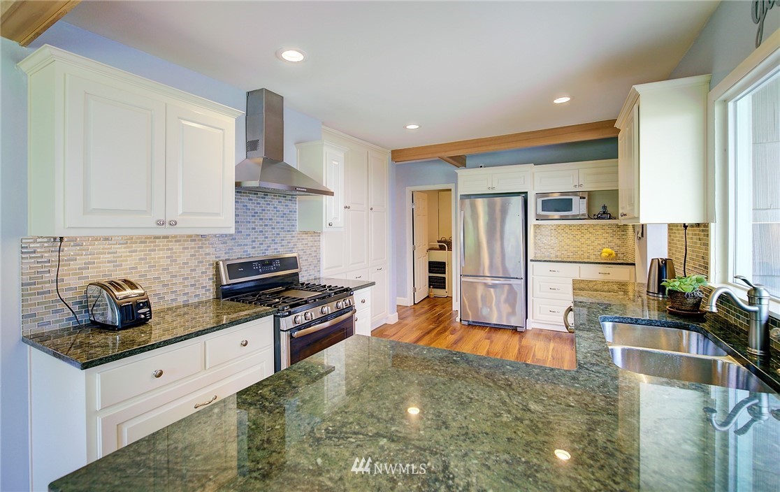 24316 Meridian Avenue South Bothell, WA 98021 - Photo 10 of 29 a kitchen with stainless steel appliances granite countertop a stove a sink a refrigerator white cabinets and wooden floor