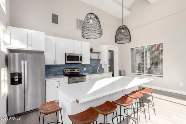 a kitchen with stainless steel appliances granite countertop a refrigerator a stove a sink dishwasher a dining table and chairs with wooden floor