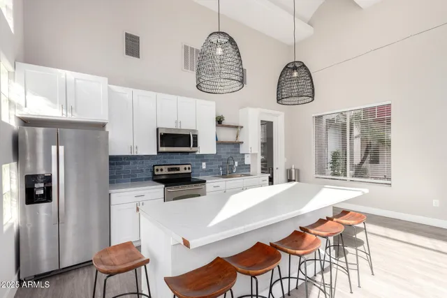 a kitchen with stainless steel appliances granite countertop a refrigerator a stove a sink dishwasher a dining table and chairs with wooden floor