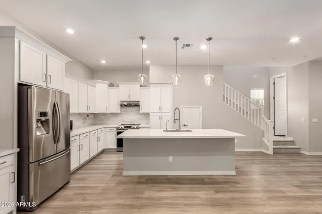 a large kitchen with stainless steel appliances a large counter top a stove and a wooden floors