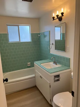 a bathroom with a granite countertop sink a toilet and mirror