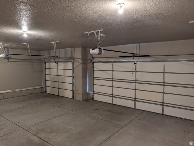171 South Mustang Road East Grantsville, UT 84029 - Photo 36 of 41 Spacious garage featuring two overhead garage doors with automatic openers, concrete flooring, painted walls, and ceiling-mounted lighting