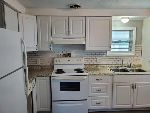 a kitchen with granite countertop white cabinets and white appliances