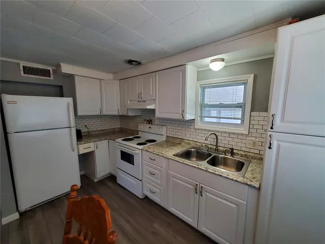 a kitchen with a sink a refrigerator and cabinets
