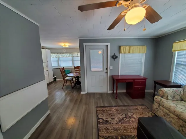 a living room with furniture and a dining table with wooden floor