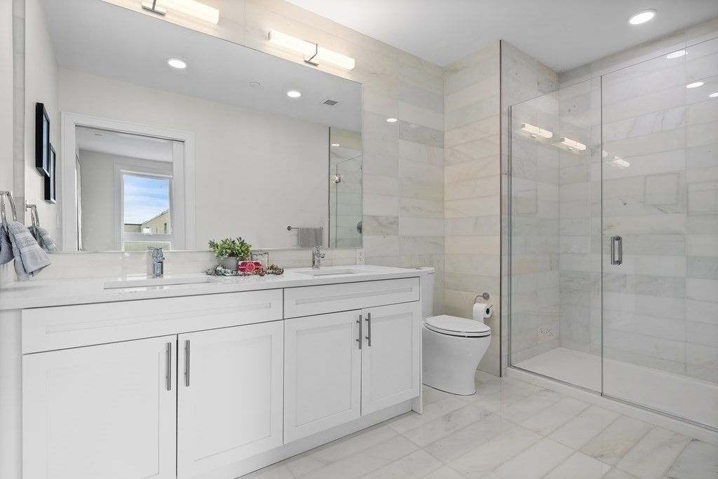301 Border Street, Unit 406 Boston, MA 02128 - Photo 16 of 38 a bathroom with a double vanity sink toilet and shower
