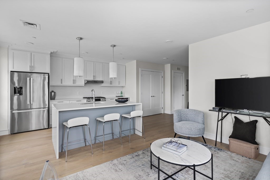 301 Border Street, Unit 406 Boston, MA 02128 - Photo 10 of 38 a living room with furniture a flat screen tv and kitchen view