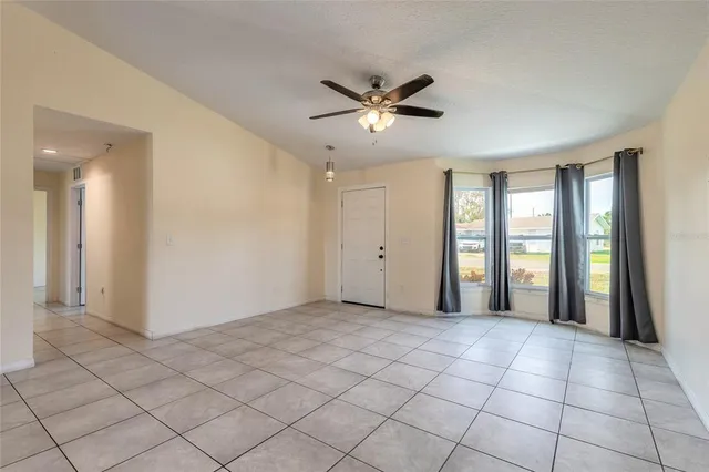 a view of a livingroom with a chandelier fan and windows