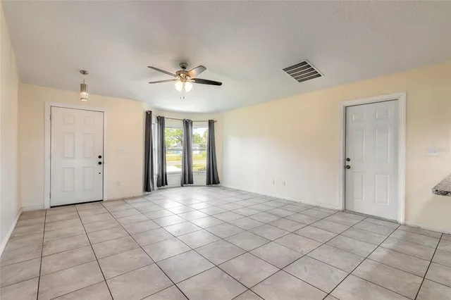 a view of an empty room with window and chandelier fan