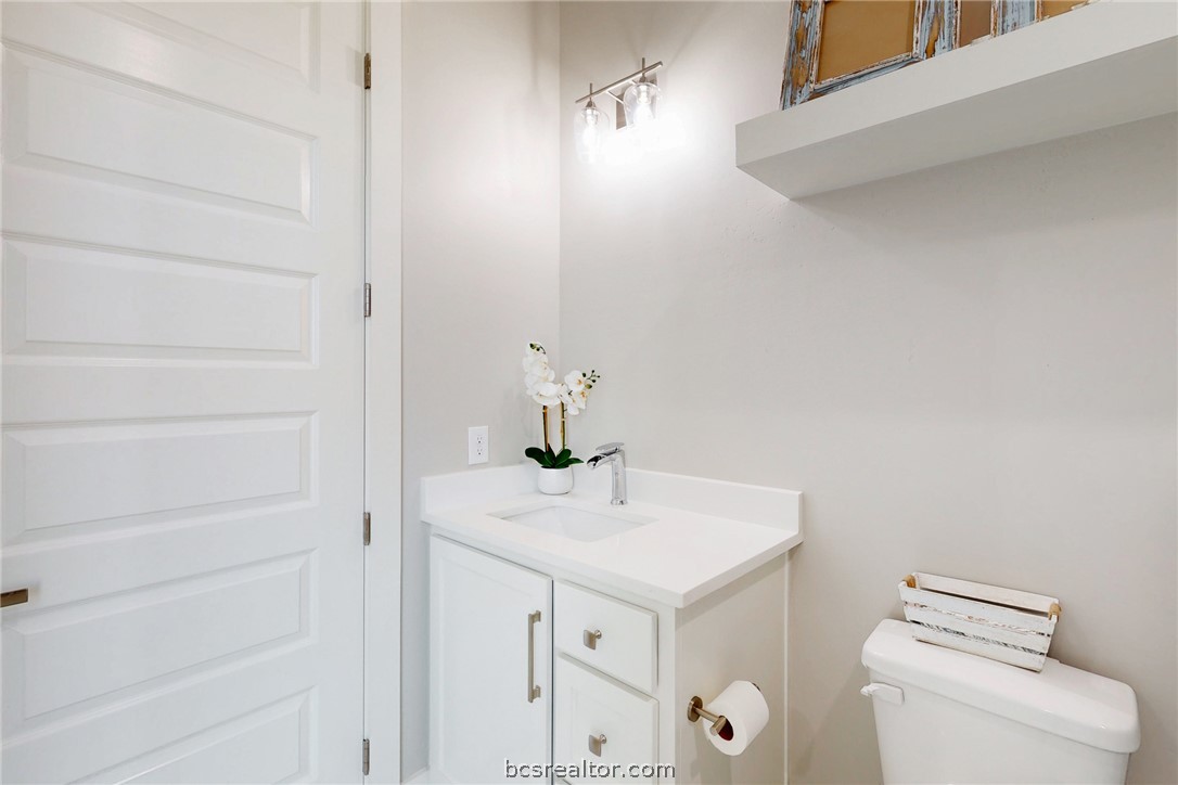 13504 Hudson Farms Road Hearne, TX 77859 - Photo 17 of 48 White paneled door opening to a bathroom featuring a white vanity with an integrated sink, polished chrome faucet, and white countertop