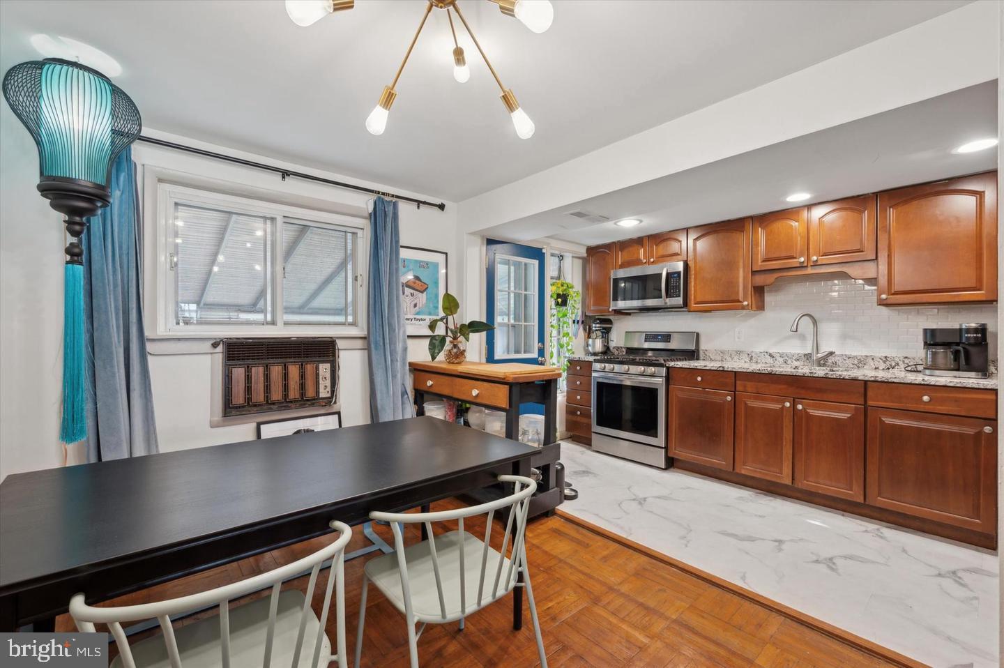 4572 Manayunk Avenue Philadelphia, PA 19128 - Photo 10 of 22 a kitchen with stainless steel appliances granite countertop a stove top oven a sink dishwasher a dining table and chairs with wooden floor