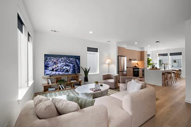 a living room with furniture kitchen view and a large window