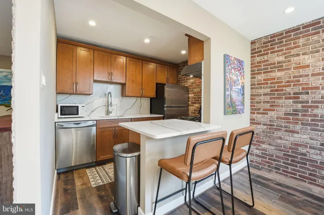 a kitchen with stainless steel appliances granite countertop a kitchen island a stove a sink and a refrigerator