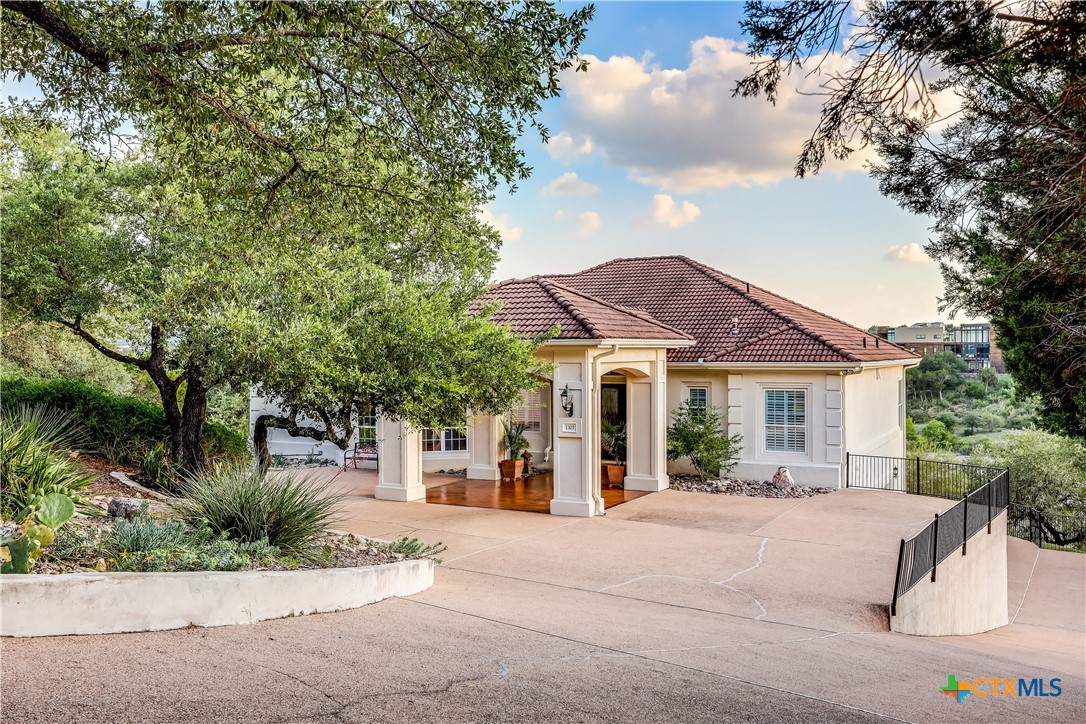 1307 Osprey Ridge Loop Lago Vista, TX 78645 - Photo 2 of 40 a view of a white house with a large tree and plants
