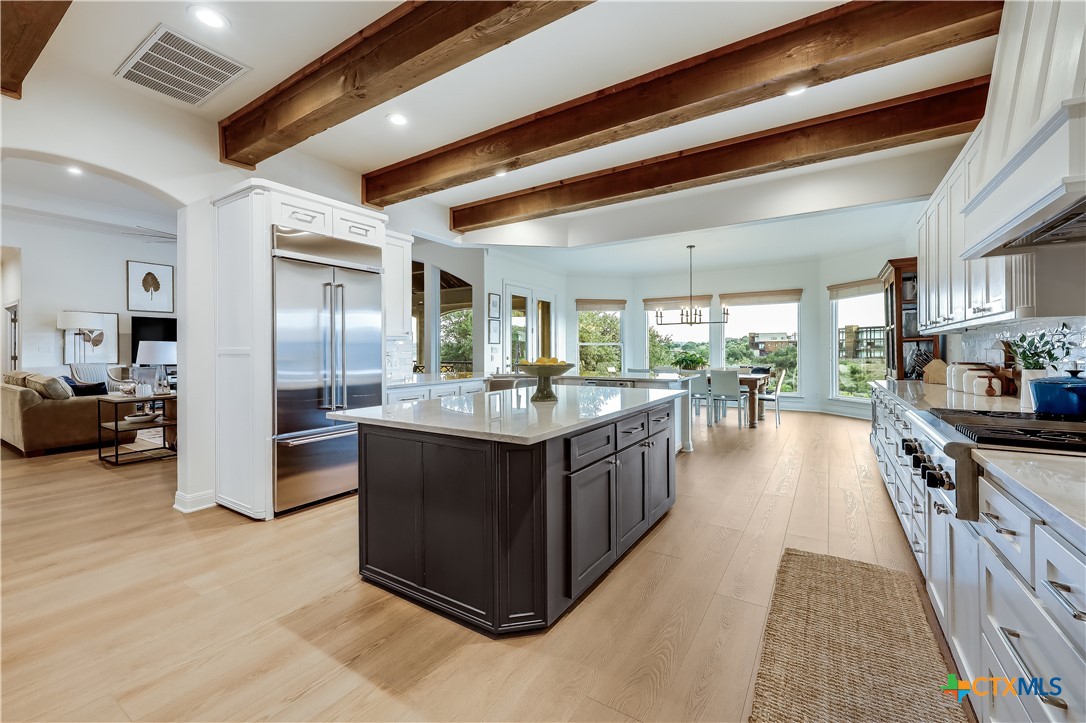 1307 Osprey Ridge Loop Lago Vista, TX 78645 - Photo 10 of 40 a kitchen with stainless steel appliances granite countertop a stove top oven a refrigerator a sink and dishwasher with wooden floor