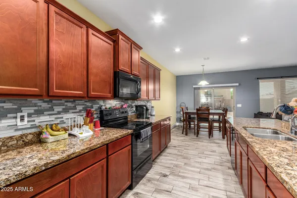 a kitchen with stainless steel appliances granite countertop sink stove top oven and cabinets