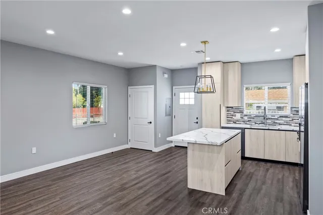 a large kitchen with kitchen island granite countertop wooden floor white cabinets and stainless steel appliances
