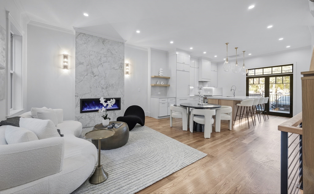 a living room with furniture kitchen view and a wooden floor