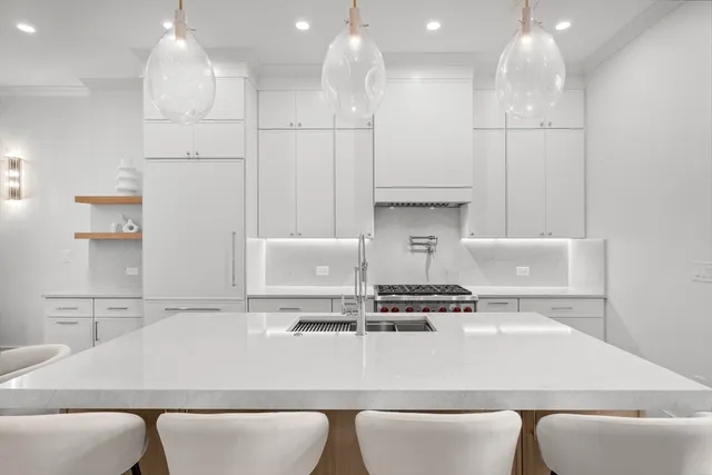 a kitchen with kitchen island granite countertop a sink a stove a dining table and chairs