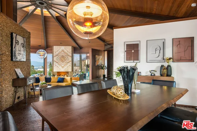 a living room with dining table a large window and potted plants