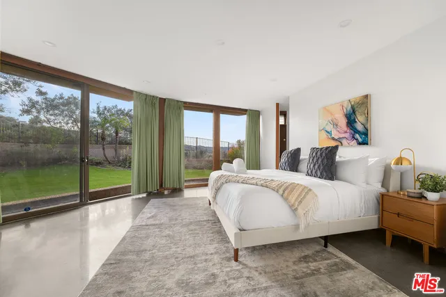 a bed sitting in a bedroom next to a large window