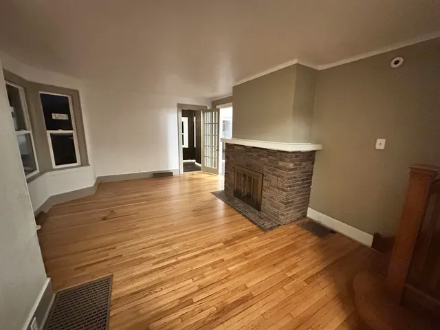 a view of an empty room with wooden floor and staircase