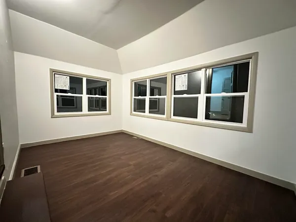 a view of an empty room with wooden floor and windows