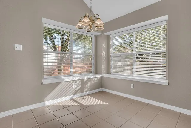 a view of an empty room with stairs and a chandelier fan