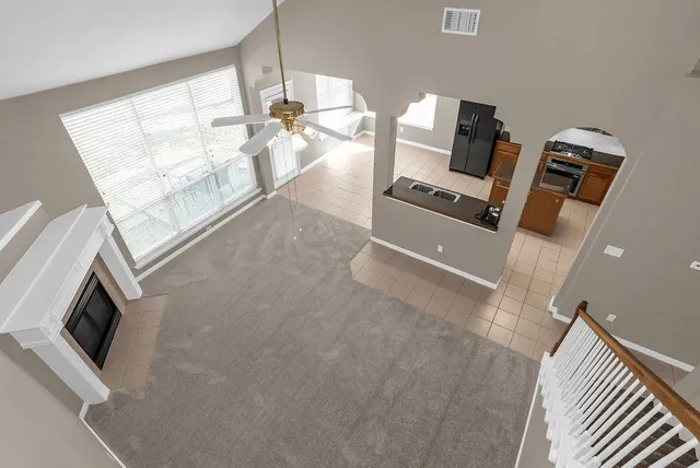 a view of an empty room with chandelier fan and fire place