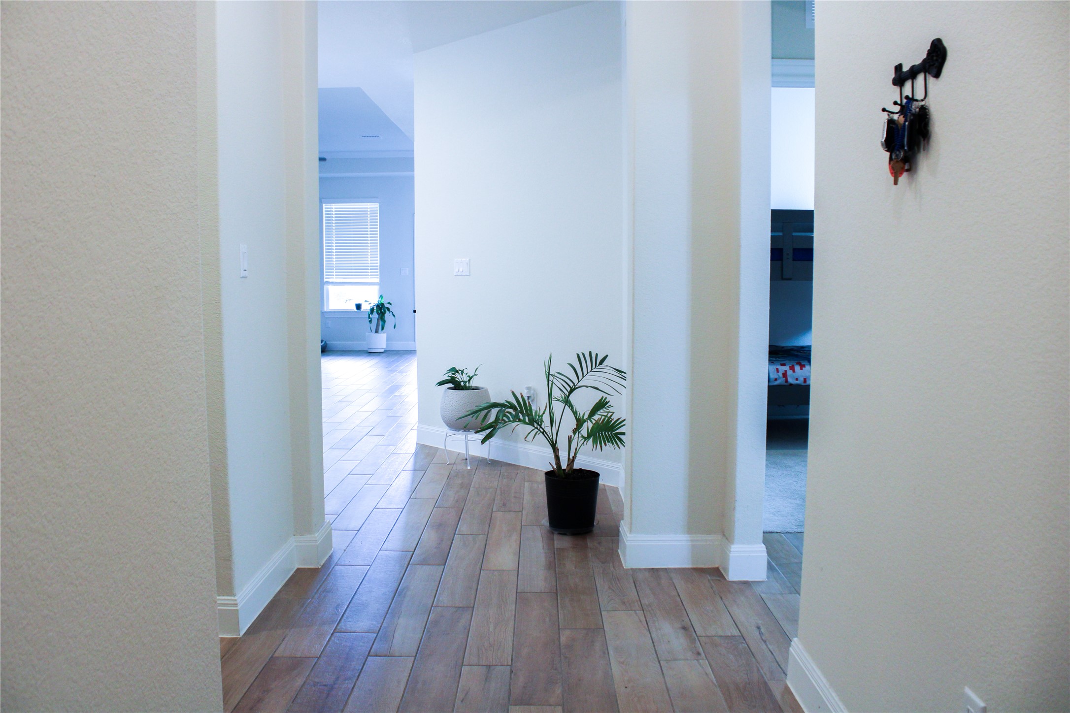 Warm wood-look flooring guides visitors through a welcoming entryway with arched openings.