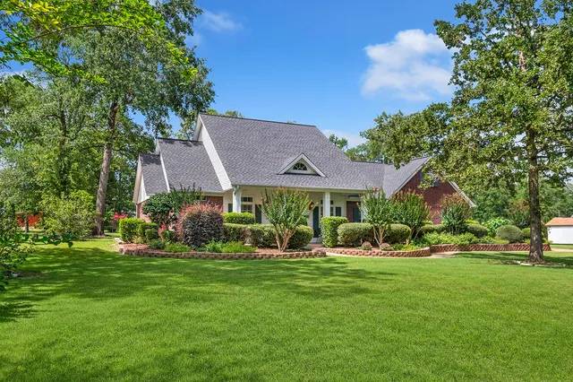 a view of a house with a big yard and potted plants and large trees