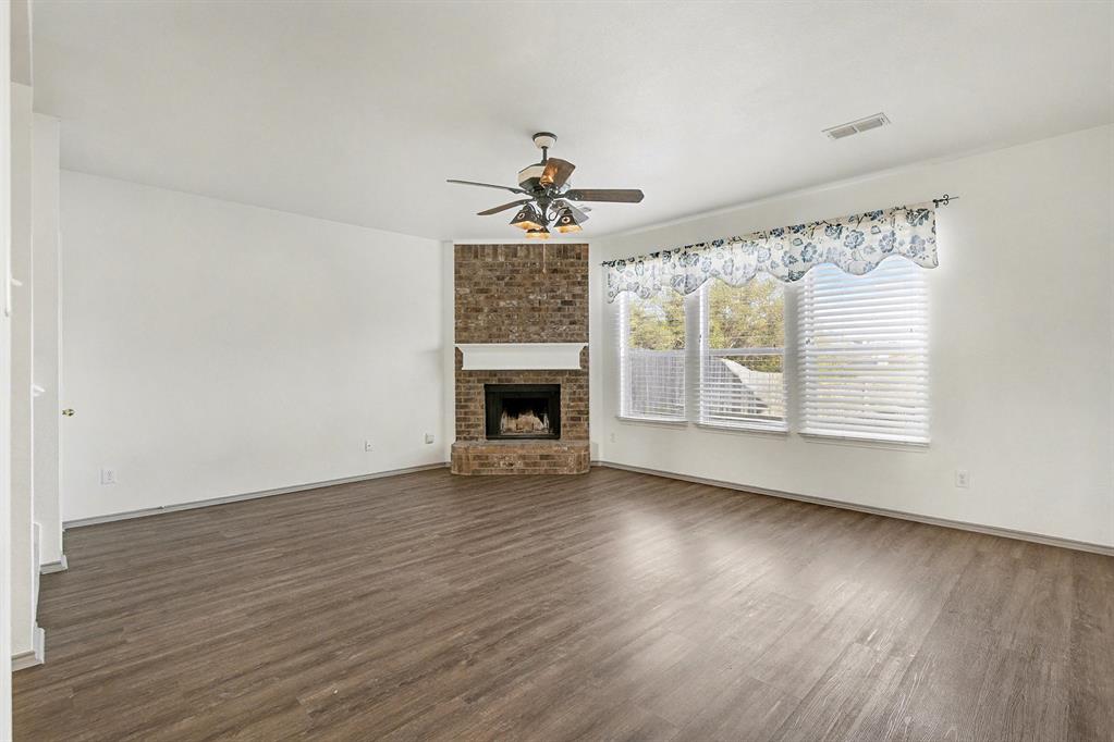 415 Hidden Ridge Drive Burleson, TX 76028 - Photo 13 of 38 an empty room with wooden floor chandelier fan and windows