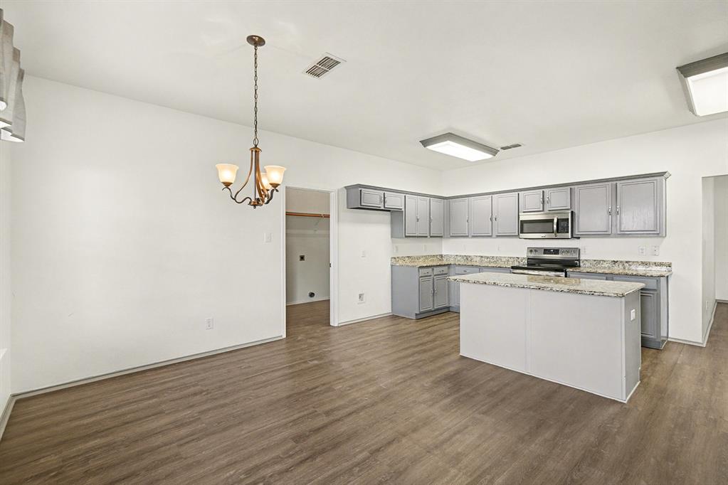 415 Hidden Ridge Drive Burleson, TX 76028 - Photo 7 of 38 a kitchen with kitchen island white cabinets and stainless steel appliances