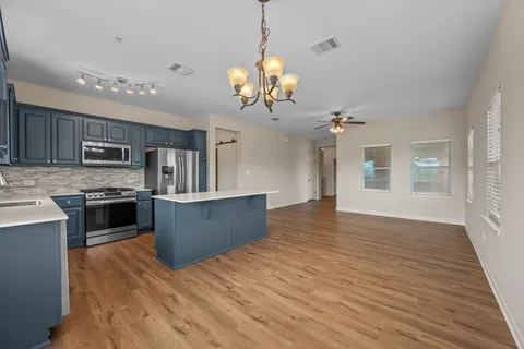 a view of a kitchen with stainless steel appliances granite countertop a sink refrigerator and a stove top oven