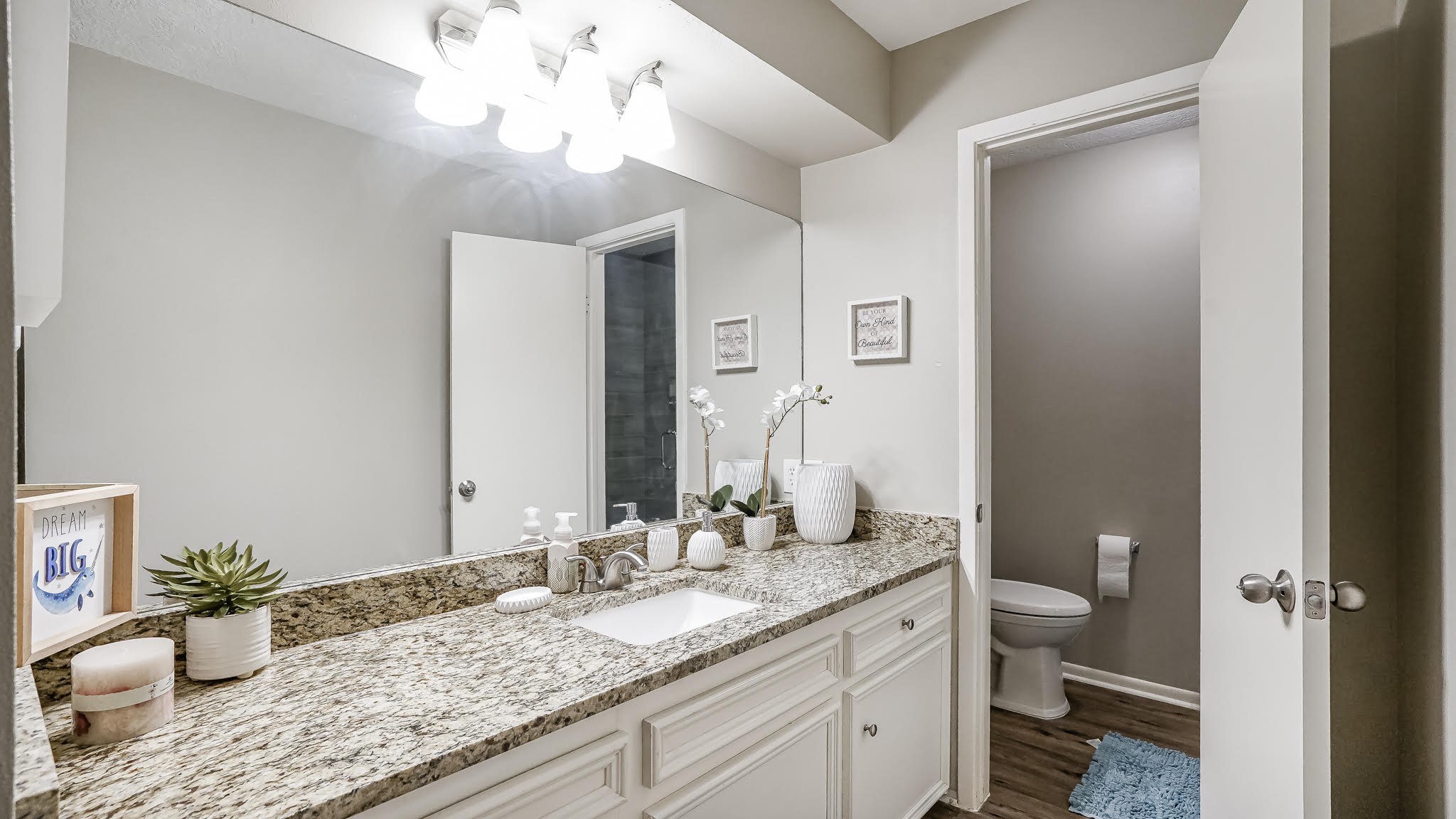 129 Capetown Conroe, TX 77356 - Photo 11 of 35 The en-suite bathroom for the first bedroom has laminate wood floors and granite counters.