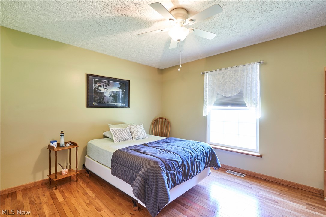 1963 Haines Road Madison, OH 44057 - Photo 19 of 34 Bedroom featuring wood-finish flooring, a ceiling fan, and a window with white trim