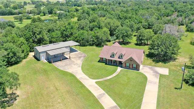 an aerial view of a house with swimming pool and tennis court