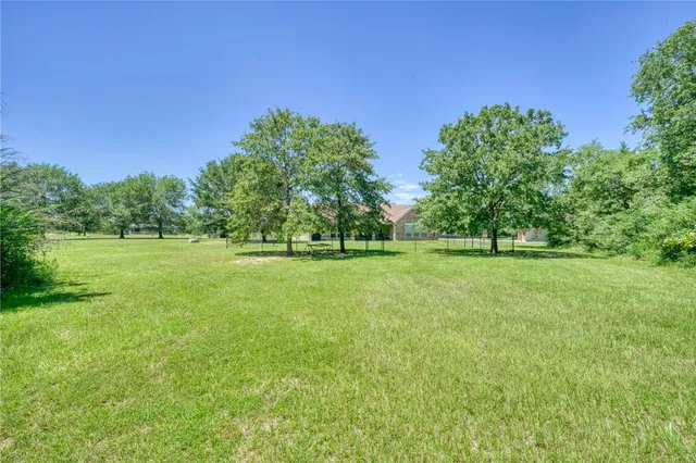 a view of a green field with trees in the background
