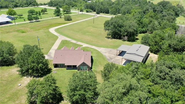 an aerial view of a residential houses with outdoor space and trees