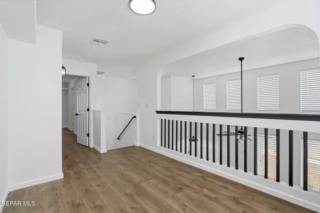 an empty room with wooden floor and windows