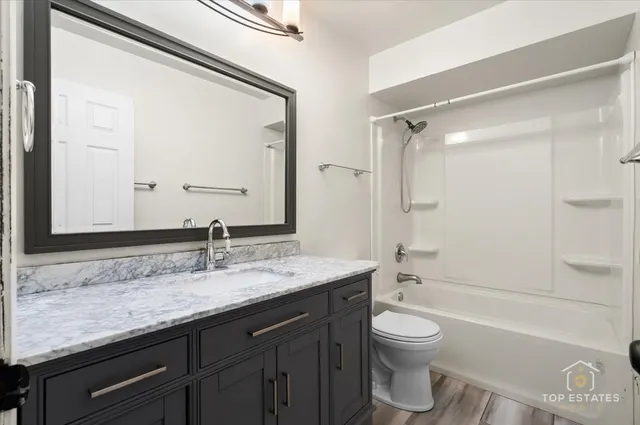 a bathroom with a granite countertop sink toilet a large mirror a bathtub and shower