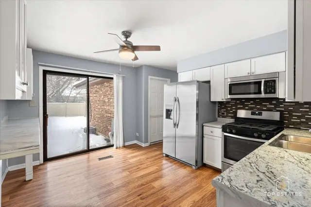 a kitchen with granite countertop a refrigerator and a stove top oven