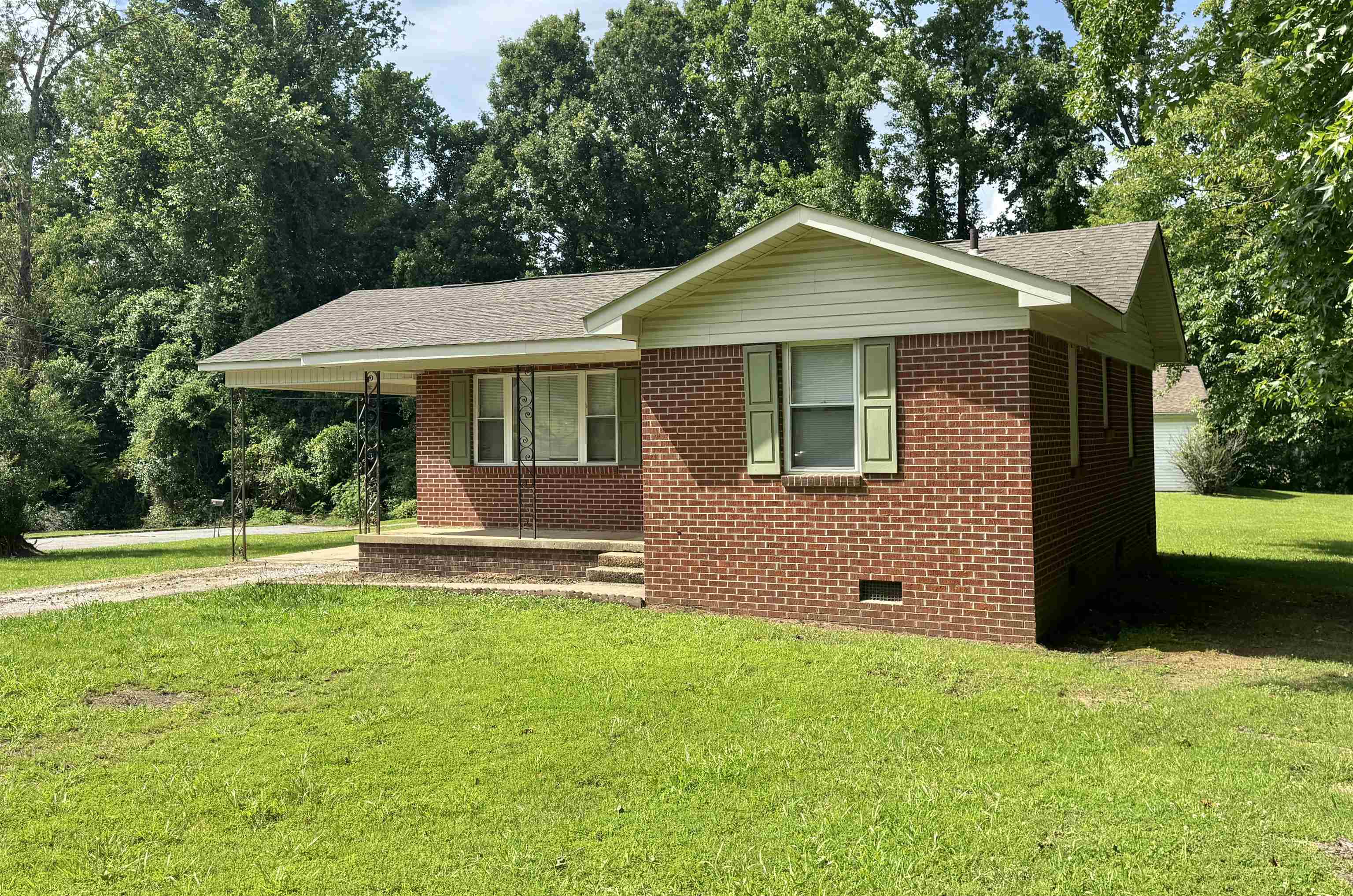 Single story home featuring crawl space, roof with shingles, a front lawn, brick siding, and a carport