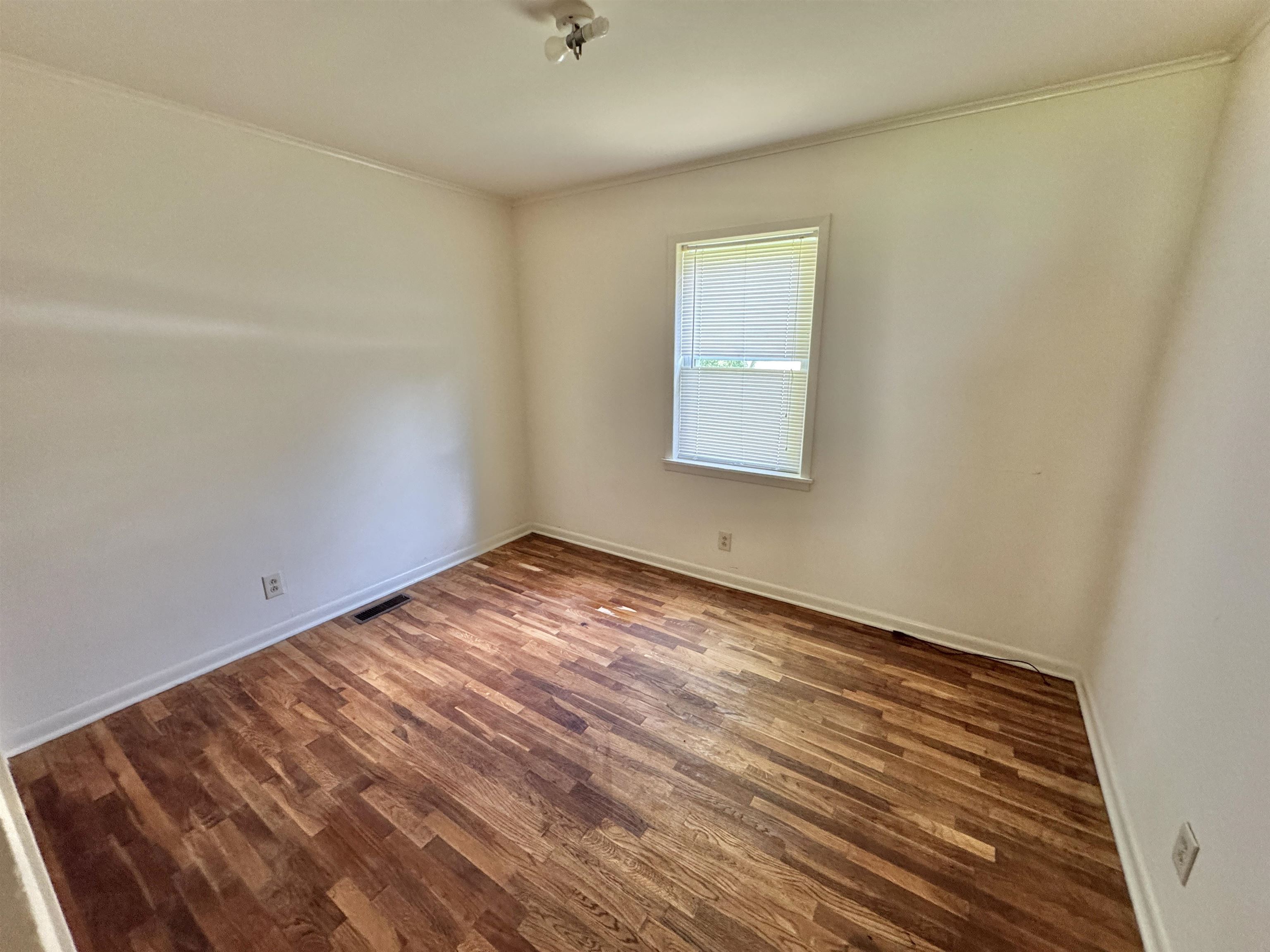 Spare room with wood finished floors and ornamental molding