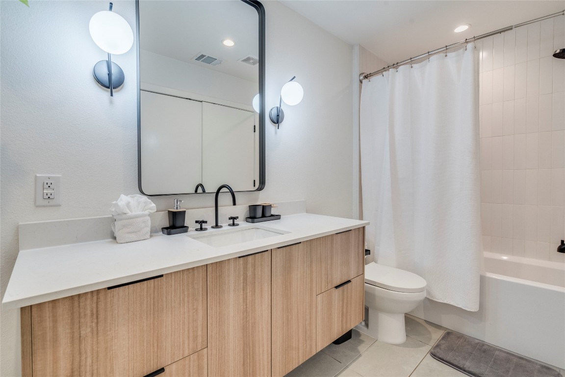 1902 Albury Cove, Unit C Austin, TX 78758 - Photo 11 of 25 a bathroom with a granite countertop sink a toilet and a mirror