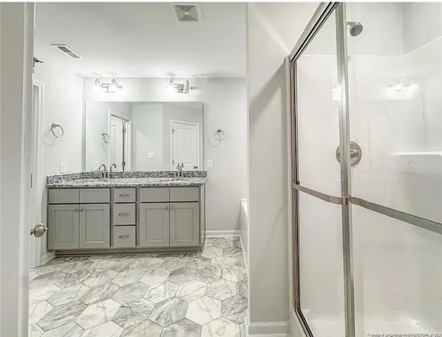 a bathroom with a granite countertop sink a mirror and a shower