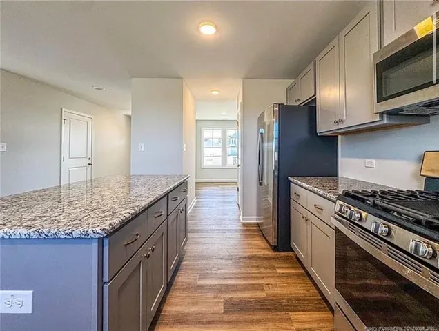 a kitchen with stainless steel appliances granite countertop a stove a sink and a microwave