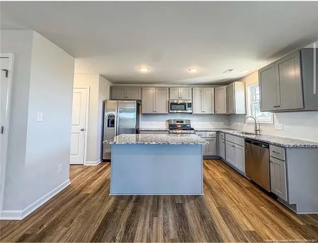 a kitchen with granite countertop a sink cabinets stainless steel appliances and a counter top space